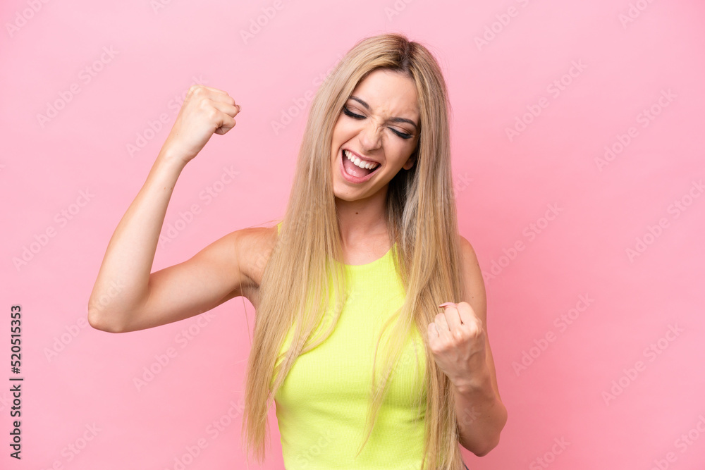 Pretty blonde woman isolated on pink background celebrating a victory Pretty blonde woman isolated on pink background celebrating a victory