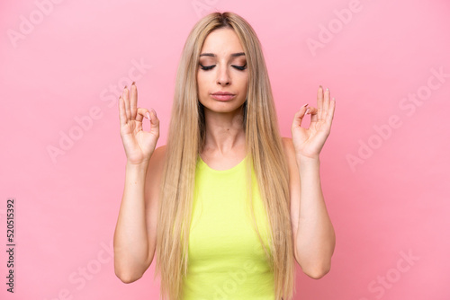 Pretty blonde woman isolated on pink background in zen pose