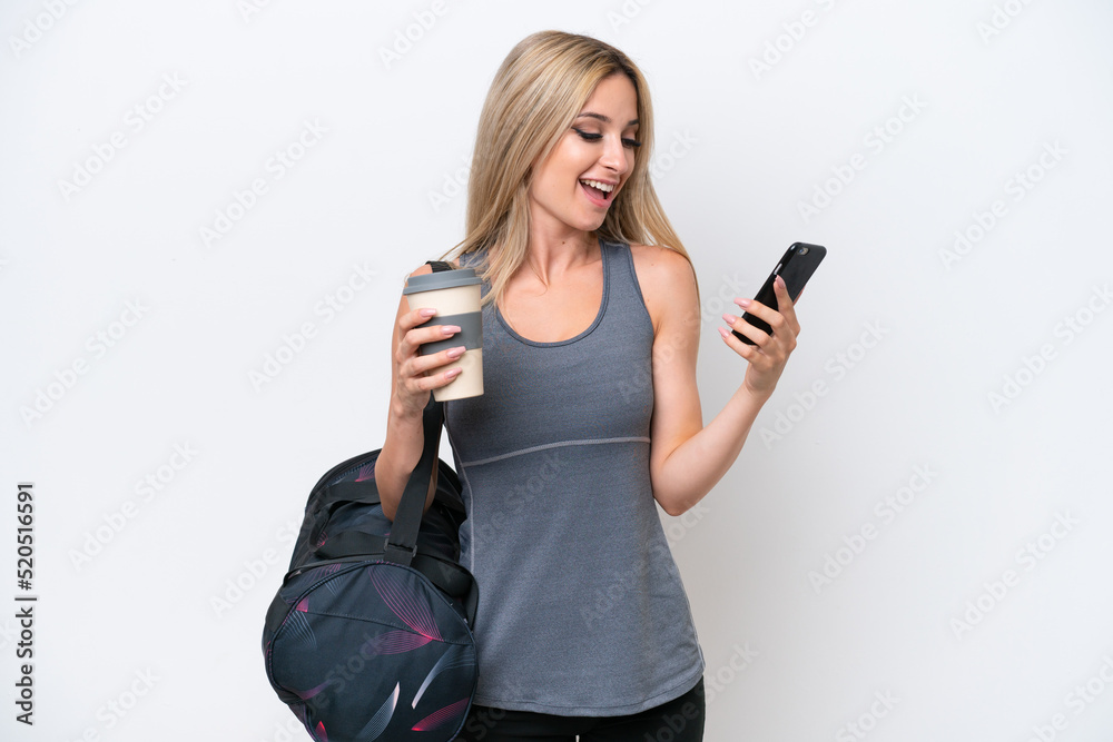 Young sport woman with sport bag isolated on white background holding coffee to take away and a mobile Young sport woman with sport bag isolated on white background holding coffee to take away and a mobile