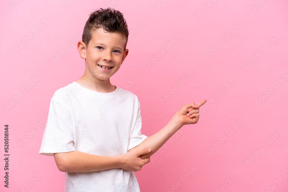 Little caucasian boy isolated on pink background pointing finger to the side Little caucasian boy isolated on pink background pointing finger to the side