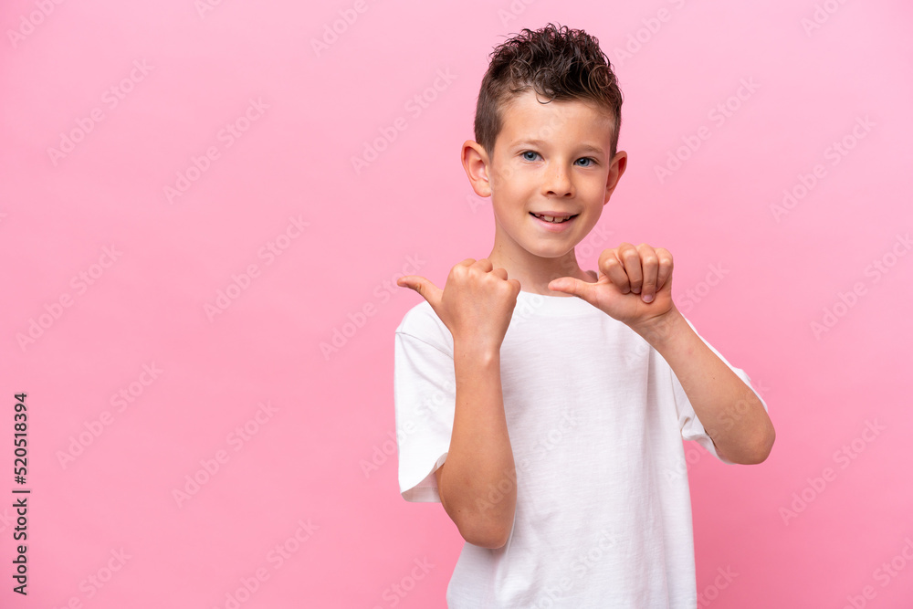 Little caucasian boy isolated on pink background pointing to the side to present a product Little caucasian boy isolated on pink background pointing to the side to present a product