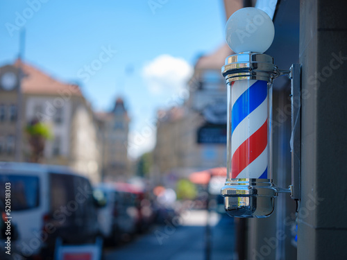 Old Fashioned Barbershop Pole over city street. International barbershop pole sign. A barber pole calling for people at street. Vintage barbershop. Salon