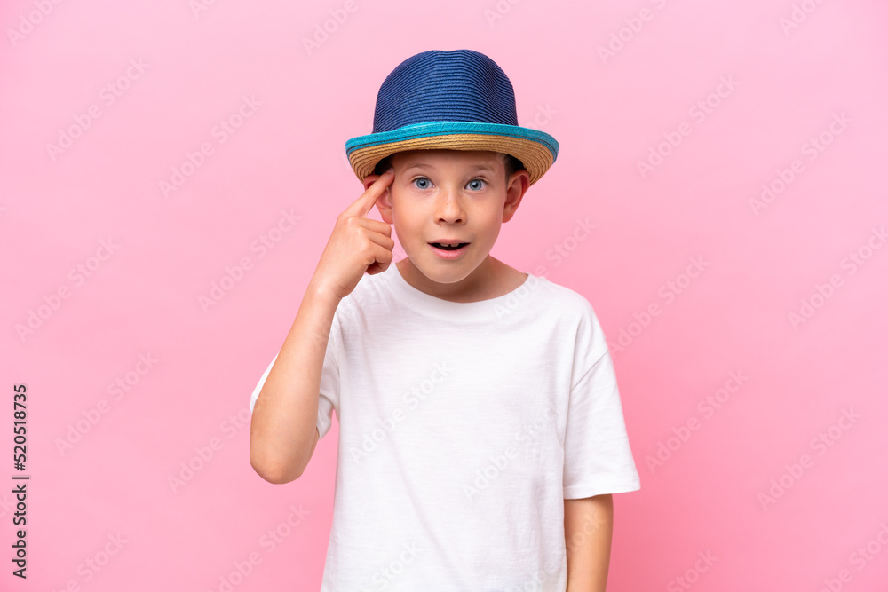 Little caucasian boy wearing a hat isolated on pink background intending to realizes the solution Little caucasian boy wearing a hat isolated on pink background intending to realizes the solution
