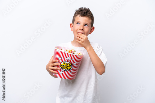 Little caucasian boy isolated on white background holding a big bucket of popcorns
