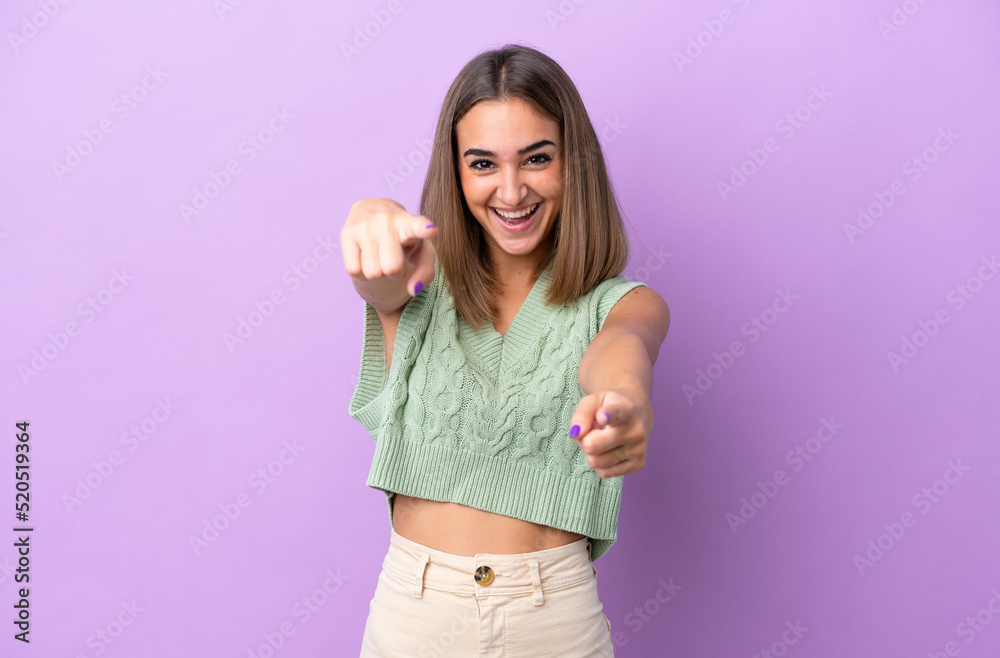 Young caucasian woman isolated on purple background surprised and pointing front Young caucasian woman isolated on purple background surprised and pointing front
