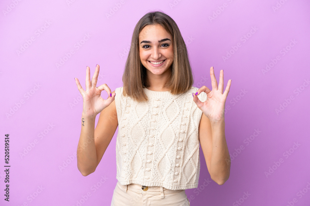 Young caucasian woman isolated on purple background showing ok sign with two hands Young caucasian woman isolated on purple background showing ok sign with two hands