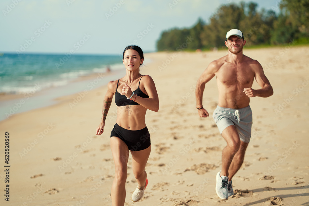 Healthy lifestyle. Jogging outdoors. Young man and woman is running on the sand beach. Healthy lifestyle. Jogging outdoors. Young man and woman is running on the sand beach.