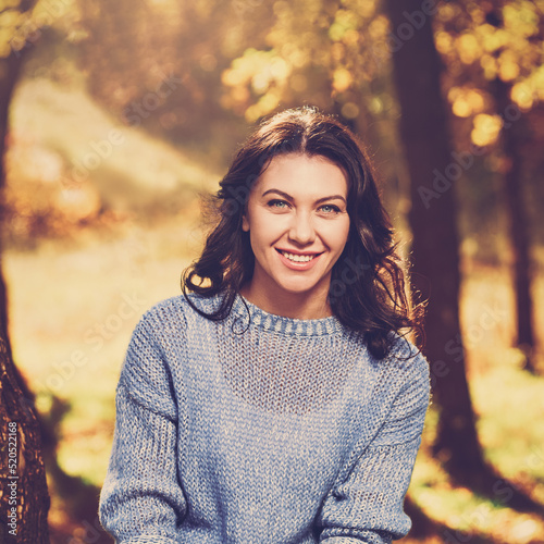 Beautiful young smiling girl posing in warm autumn forest