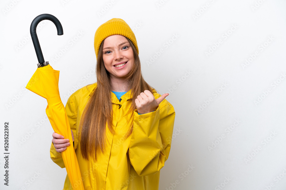 Young caucasian woman with rainproof coat and umbrella isolated on white background pointing to the side to present a product Young caucasian woman with rainproof coat and umbrella isolated on white background pointing to the side to present a product