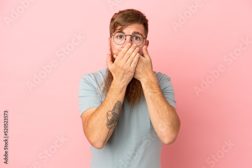 Fototapeta Naklejka Na Ścianę i Meble -  Young reddish caucasian man isolated on pink background covering mouth with hands