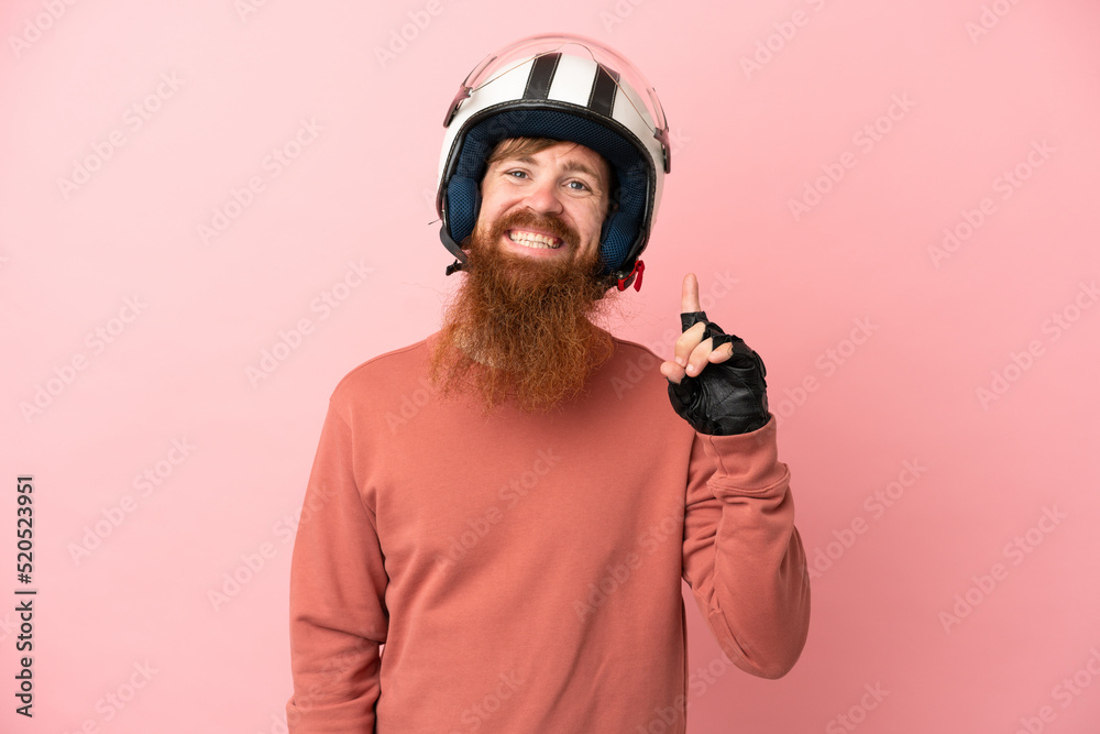 Young reddish caucasian man with a motorcycle helmet isolated on pink background showing and lifting a finger in sign of the best Young reddish caucasian man with a motorcycle helmet isolated on pink background showing and lifting a finger in sign of the best