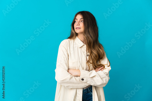 Young caucasian woman isolated on blue background looking to the side