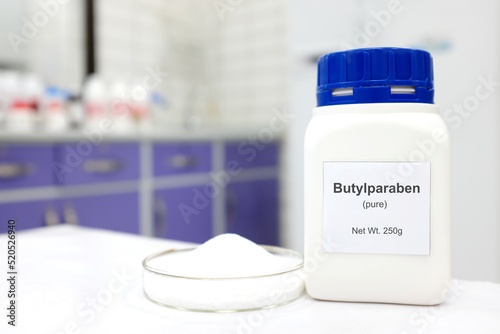 Selective focus of a bottle of butylparaben paraben pure chemical compound used as preservative in cosmetics and pharmaceutical products. White laboratory background.