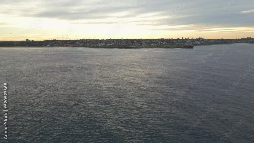 Cinematic aerial shot of drone flying low from the ocean to the coastal beach in Sydney at sunset in Australia Cinematic aerial shot of drone flying low from the ocean to the coastal beach in Sydney at sunset in Australia