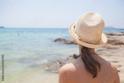 Summer holiday travel portrait. Child girl with straw hat looking seascape. 