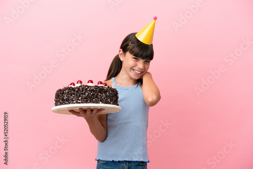 Little caucasian kid holding birthday cake isolated in pink background laughing