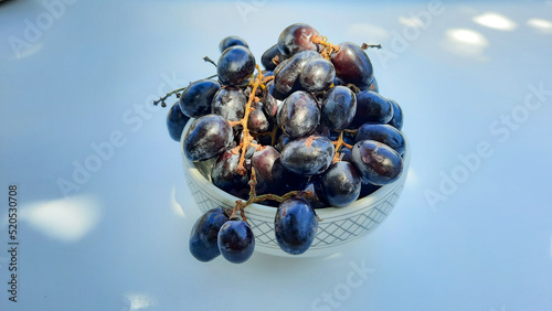 Purple grapes in bowl with stem in center isolated on white background and shadow 02