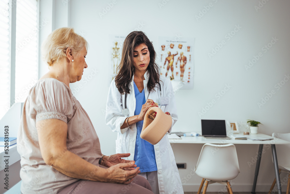 Obraz premium Young woman with injury of neck visiting doctor in clinic. Doctor examining a patient at desk in medical office. Doctor talking to a senior patient with cervical collar at the hospital