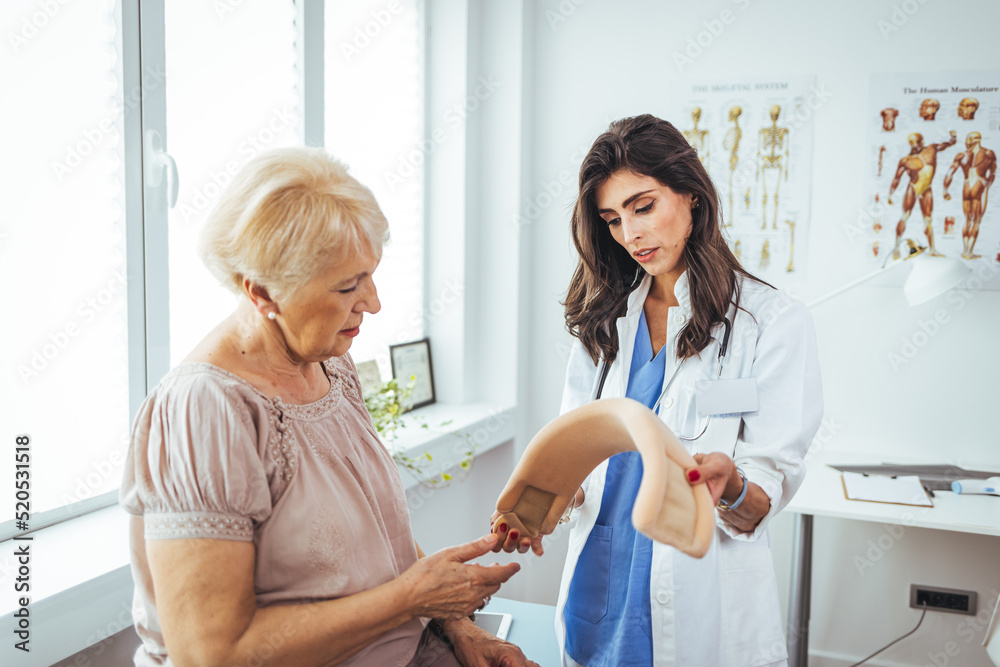 Portrait of a female doctor helping a senior woman at office with her neck injury a healthcare and medicine concepts. Doctor putting neck orthopaedic collar on adult injured woman Portrait of a female doctor helping a senior woman at office with her neck injury a healthcare and medicine concepts. Doctor putting neck orthopaedic collar on adult injured woman