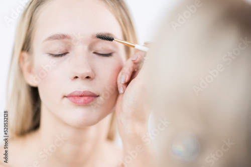 Makeup in the studio. Makeup artist draws out eyebrows. Close-up.