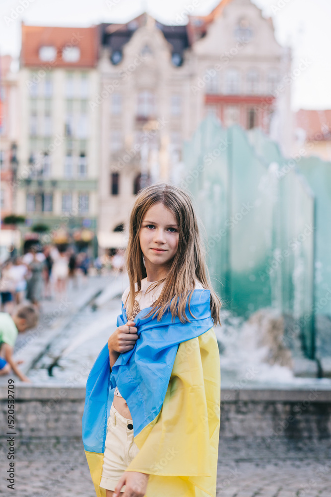 Portrait of a Ukrainian girl with a flag in her hands in the city square.