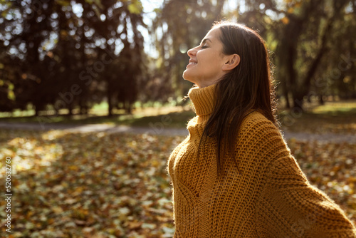 Caucasian woman with eyes closed smiling at the park in autumn photo