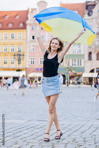 Portrait of a Ukrainian woman with a flag in her hands on the city square.