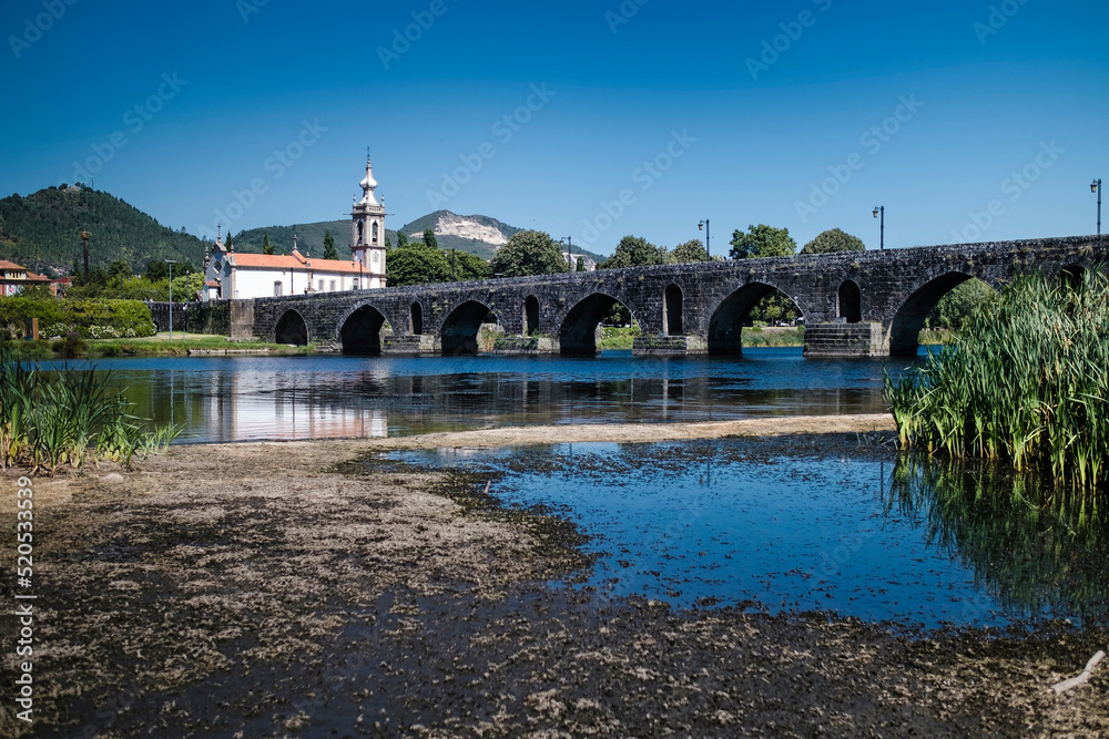 View of the long medieval bridge (ponte) that passes over the Lima river that runs next to the Ponte de Lima town, Portugal. View of the long medieval bridge (ponte) that passes over the Lima river that runs next to the Ponte de Lima town, Portugal.