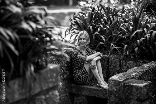 A woman on a stone bench in old parkl. Black and white photo. photo