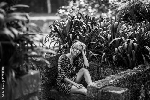 A woman sits on a stone bench in old parkl. Black and white photo. photo