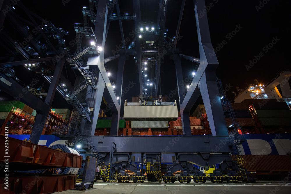 Fototapeta premium operation of container terminal at night. Unloading container ship at night. Mooring cranes unload container ship at night