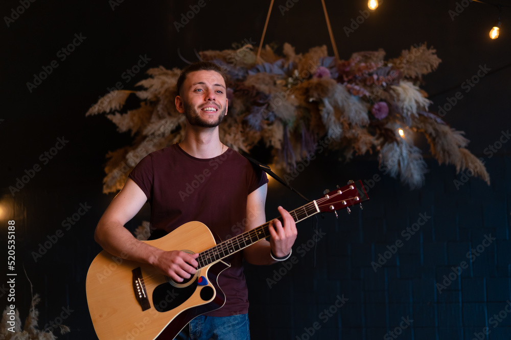 Male musician playing acoustic guitar. Guitarist plays classical guitar on stage in concert