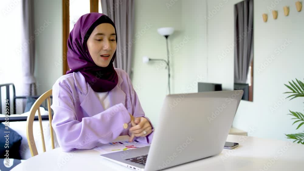 Laptop video call. Internet communication. Online chat, Smiling asia arab people young woman wear hijab headscarf talking to friend on notebook web conference on desk at home living room. Laptop video call. Internet communication. Online chat, Smiling asia arab people young woman wear hijab headscarf talking to friend on notebook web conference on desk at home living room.