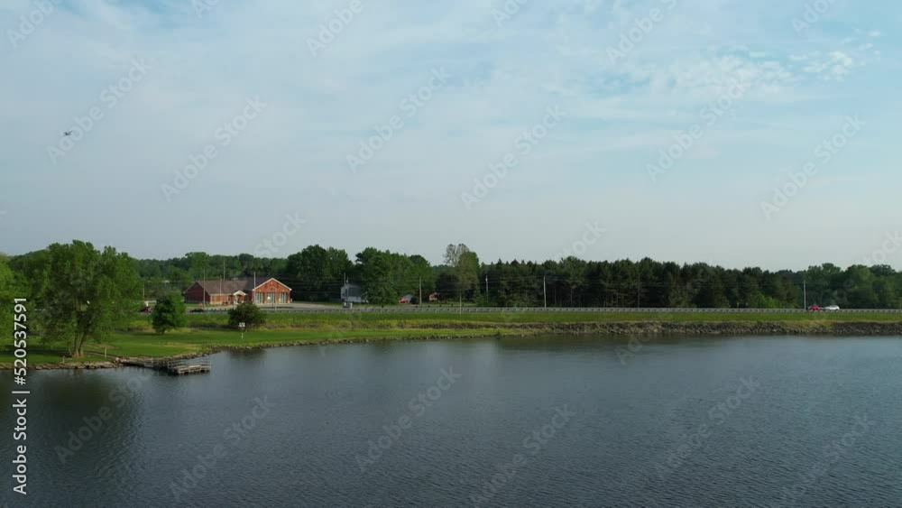 A drone shot of a sunny spring morning on meadow near river. Scenic rural landscape. A road is seen along side the lake A drone shot of a sunny spring morning on meadow near river. Scenic rural landscape. A road is seen along side the lake