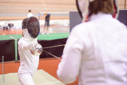 two fencers in white uniforms  are training to participate in a duel