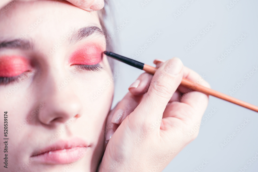 Makeup artist performs bright eye makeup in the studio. Close-up.