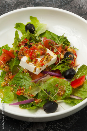 vegetable salad with pickled cheese on a white plate in a restaurant