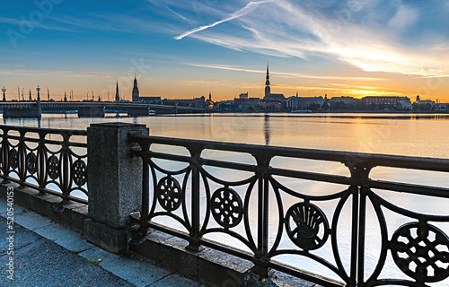 Metallic fence in waterfront of the river and stone bridge in center of Riga ...