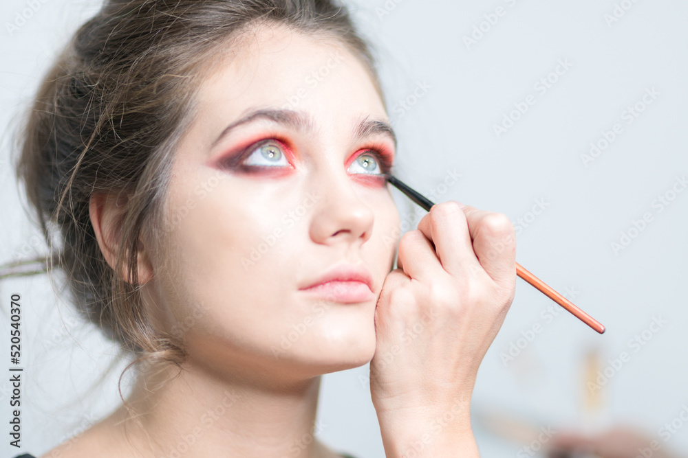 Fototapeta premium Performing bright red makeup close-up. Expressive look.