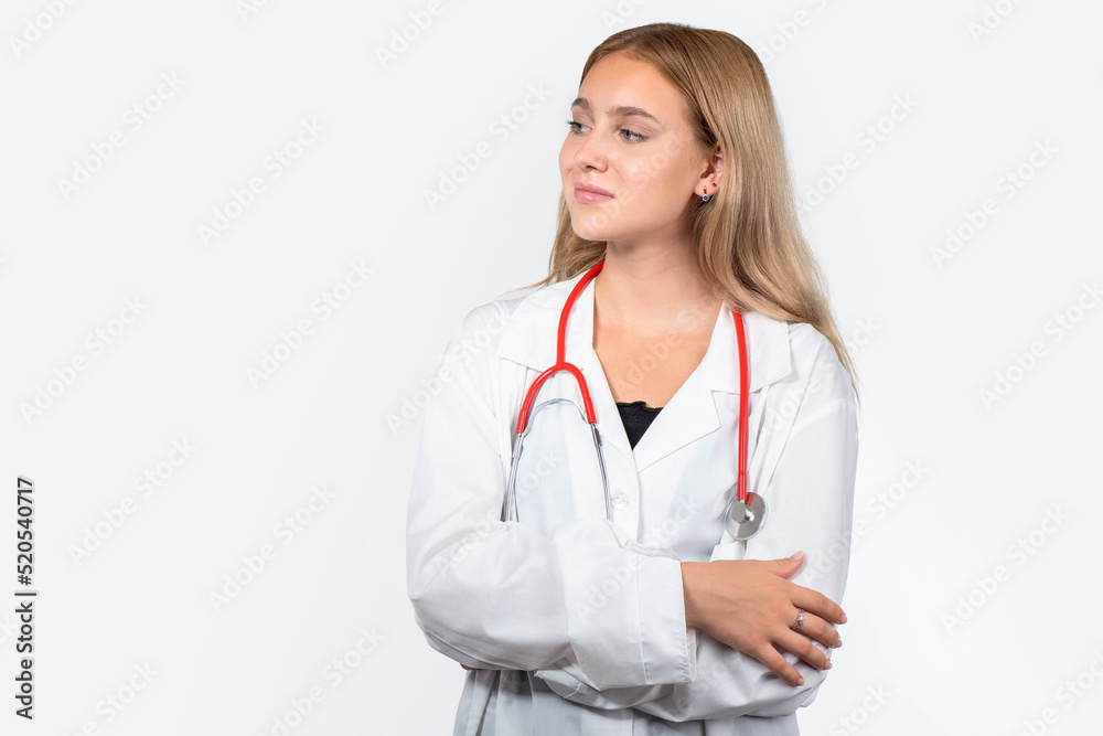 Young nurse. Blond woman in doctor uniform. Hospital worker in white coat. Girl nurse with stethoscope around her neck. Concept of career in hospital. Confident nurse stands with her arms crossed Young nurse. Blond woman in doctor uniform. Hospital worker in white coat. Girl nurse with stethoscope around her neck. Concept of career in hospital. Confident nurse stands with her arms crossed