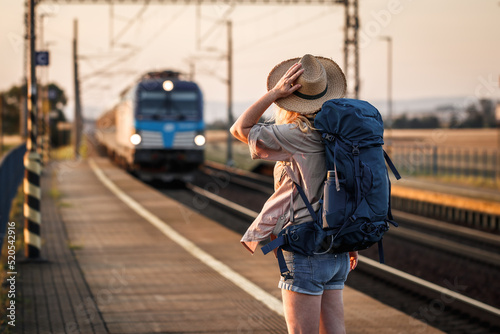 Travel by train. Woman backpacker standing at railroad station photo