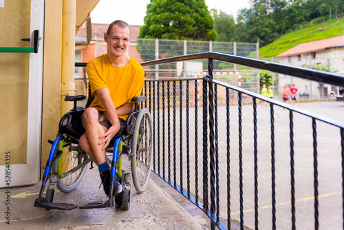 A disabled person dressed in yellow in a wheelchair in the schoolyard