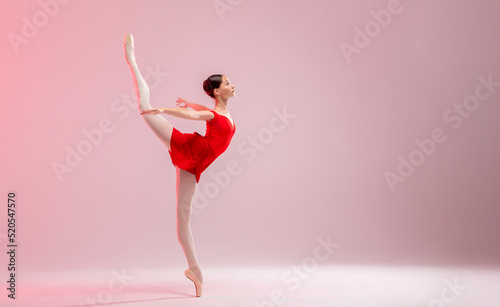 Beautiful young ballerina on a white background. The ballerina is dressed in a red leotard, pink leotards, pointe shoes.