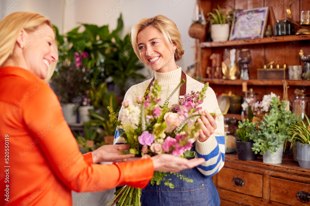 Female Customer In Florists Shop Buying Bouquet Of Flowers
