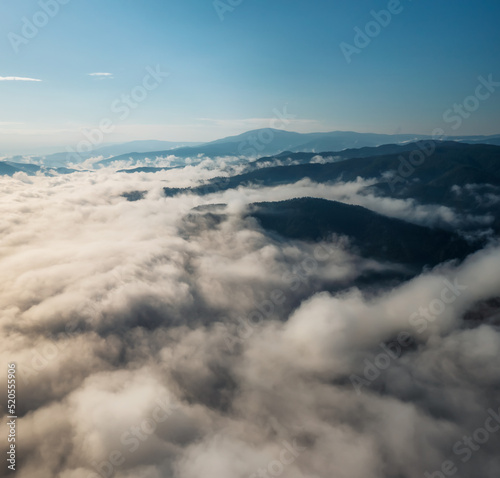 Amazing aerial view of beautiful low clouds creeping on the tree-covered mountain slopes  the Rhodopes in Bulgaria at sunrise.