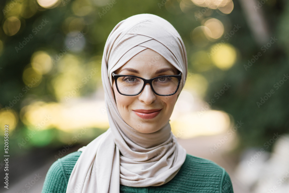 Portrait of young muslim woman wearing hijab head scarf in city park ...