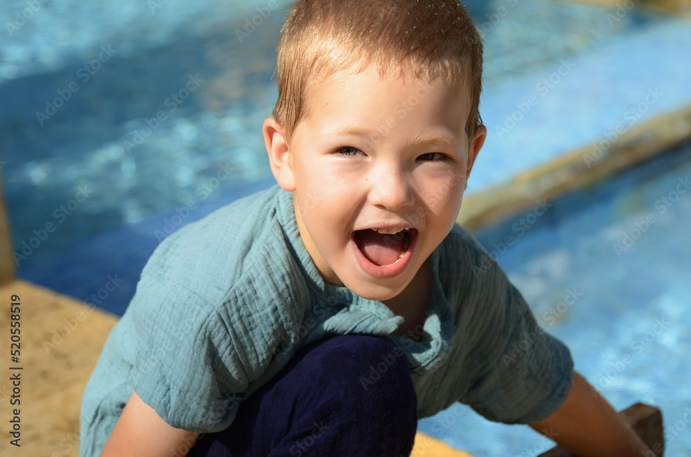 Cute positive boy smiling on the background of the pool. Joy, smile, portrait of a happy child. Cute positive boy smiling on the background of the pool. Joy, smile, portrait of a happy child.