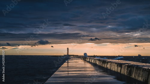Scenic landscape of sunset over Baltic sea. Cloudy sky. Mangalsala mols. Way to lighthouse. Dramatic seascape.