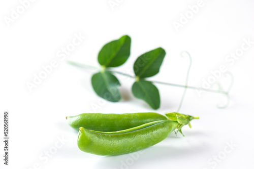 Pods of ripe green peas with leaves on a white background. Selective focus.