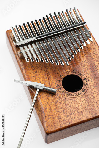 Musical instrument kalimba with a small metal hammer for tuning on a white background